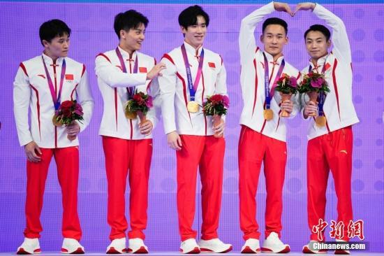 资料图：9月24日，浙江杭州，杭州亚运会体操男子资格赛暨团体决赛，中国队夺得冠军。邹敬园肖若腾合体比心，一旁的林超攀看到也举起了一只手，可惜只有“半颗心”。图/视觉中国
