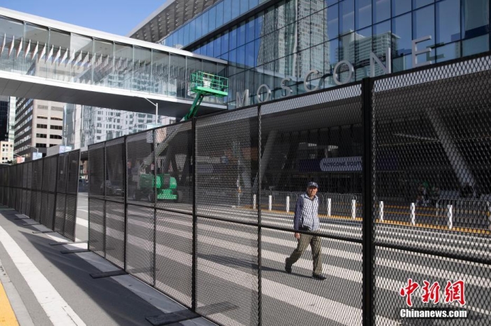 当地时间11月10日，一名行人从美国旧金山莫斯康中心周围的金属围栏旁经过。随着亚太经合组织(APEC)第三十次领导人非正式会议临近，作为会议场地的莫斯康中心附近出现金属围栏，执勤警察也大幅增加。<a target='_blank' href='/'>中新社</a>记者 刘关关 摄